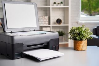 Image of a Printer/Copier on a desk with a plant.